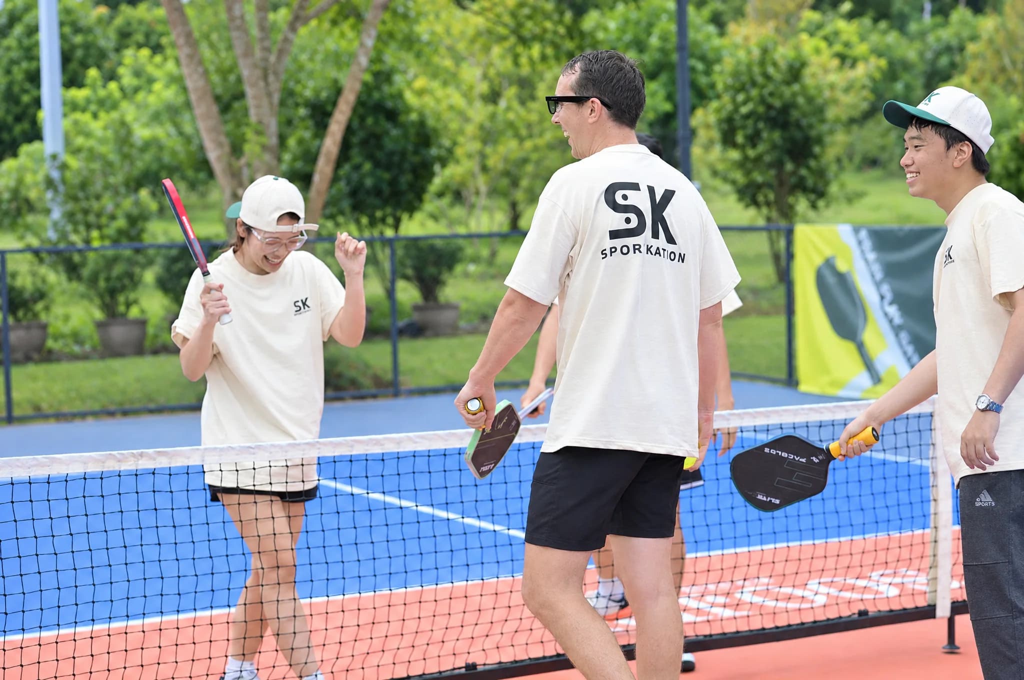 Participants smiling and talking together on the pickleball court at Soojin Resort