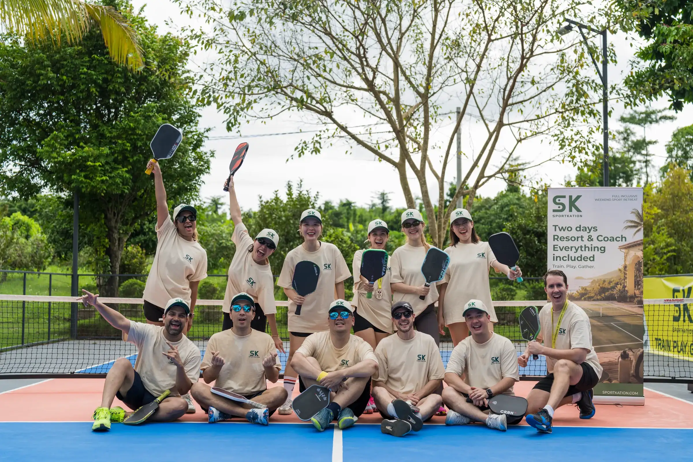 Sportkation participants posing together with paddles and medals on the Soojin Resort pickleball court