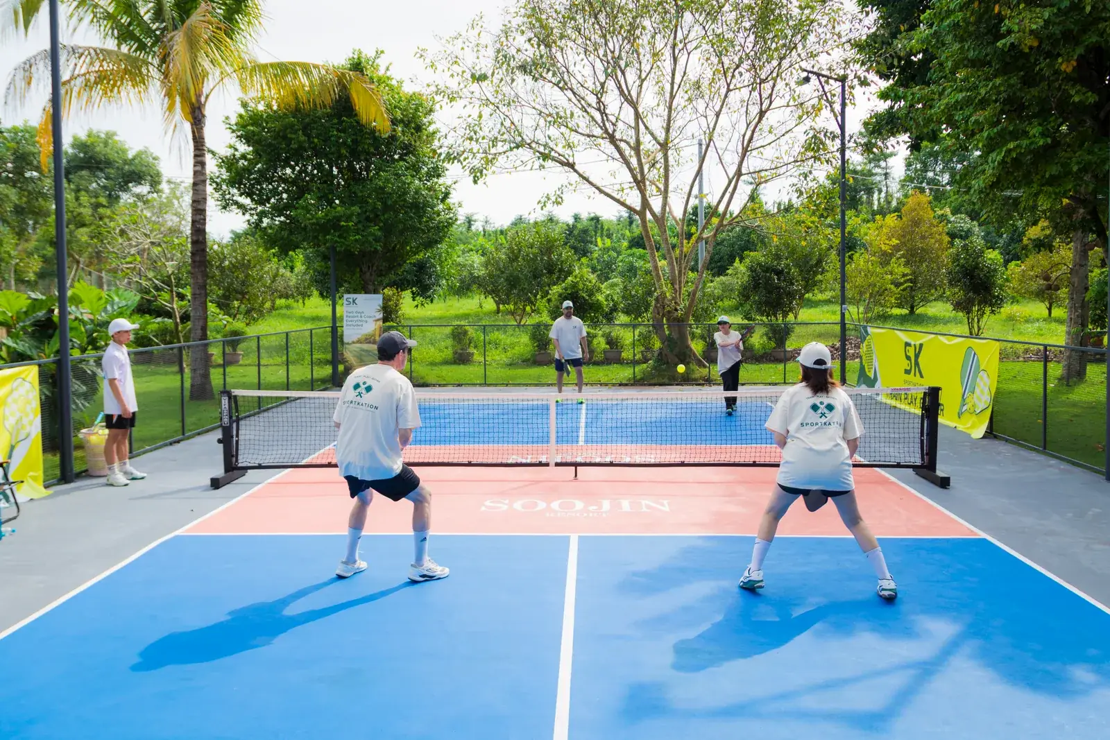 Two doubles teams playing on the blue pickleball court at Soojin Resort