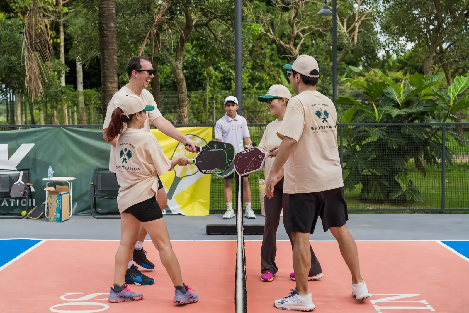 Sportkation players greeting each other with their paddles at the net