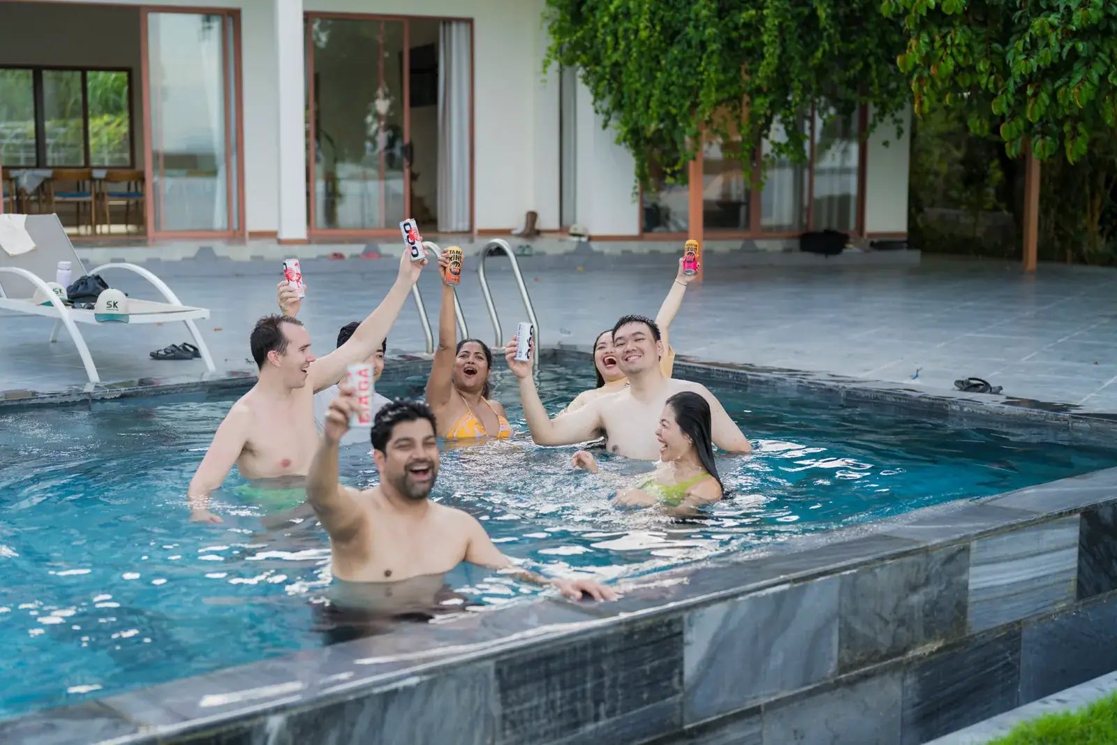 Sportkation participants raising drinks together in the pool