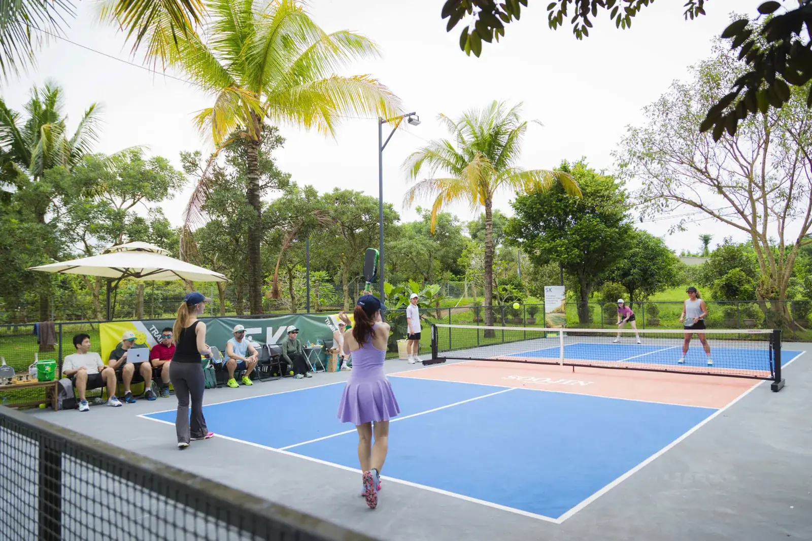 Pickleball players on the tree-lined blue courts at Soojin Resort