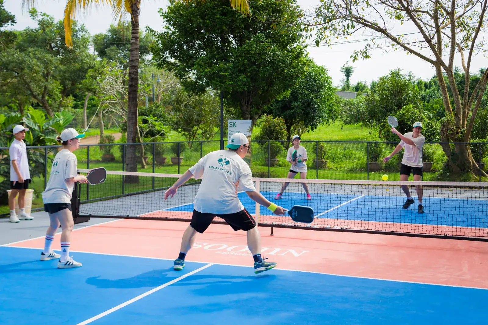Players rallying on the blue and coral pickleball court at Soojin Resort